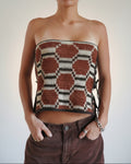 A person wearing a strapless knit tube top with a geometric hexagon pattern in brown, beige, and black, paired with brown corduroy pants.